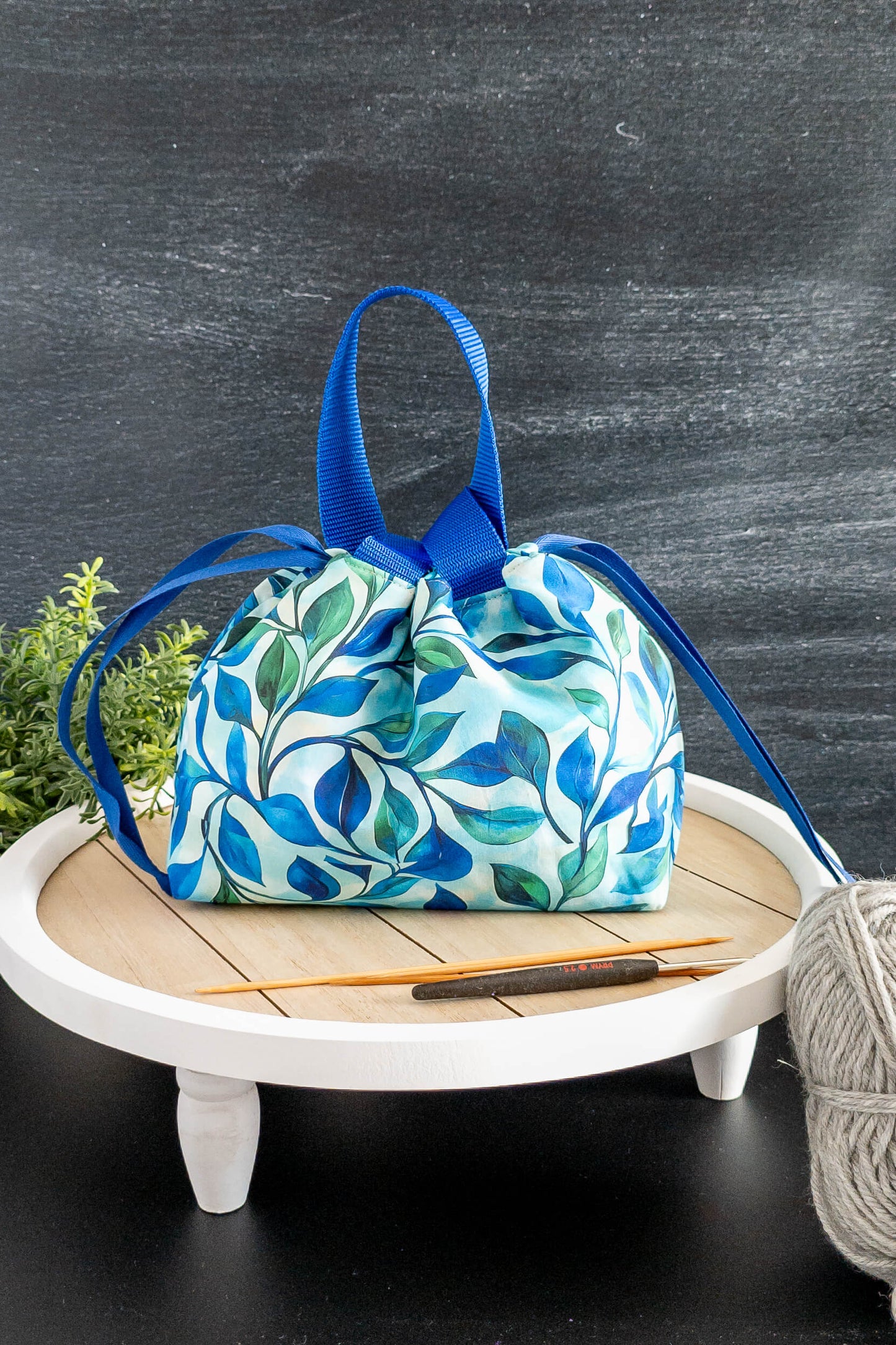 Seitenansicht der Stricktasche mit blauen Tragegriffen, ideal zum Transport deiner Wolle.