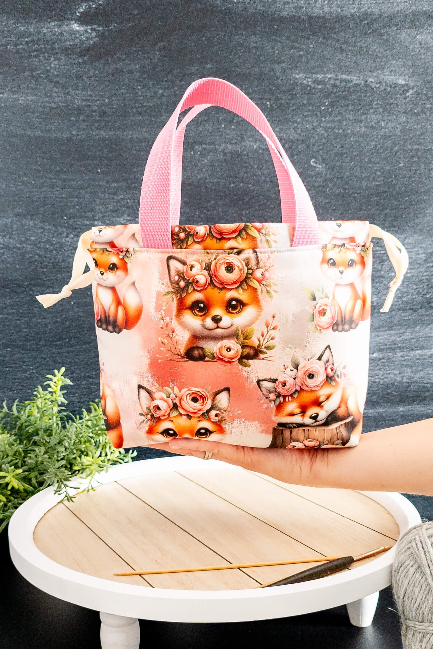 Die Alva Bag Foxy Bloom auf einem Tisch mit Strickzubehör – stilvoll und praktisch zugleich.