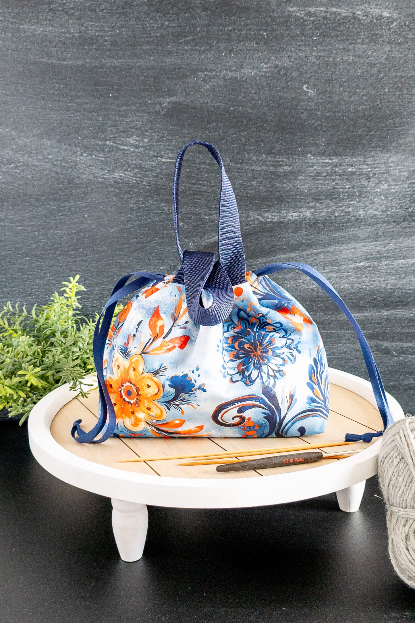 Produktbild der Tasche im Tageslicht mit Wollknäuel und Stricknadeln als stilvolle Deko