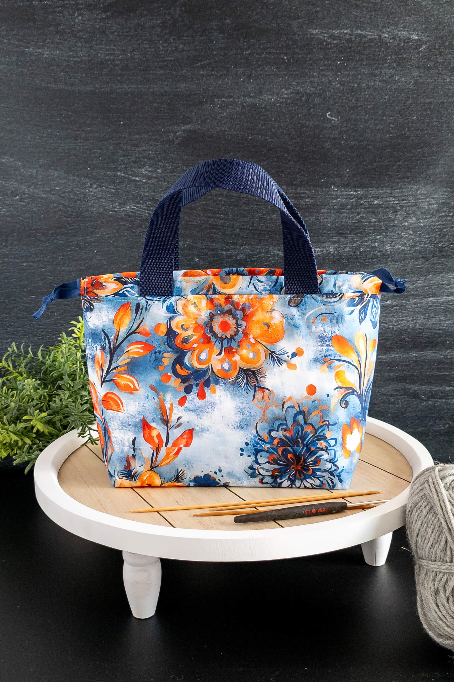 Projekttasche Alva Bag Nordic Bloom mit floralen Mustern in Blau und Orange, Vorderansicht auf Tisch
