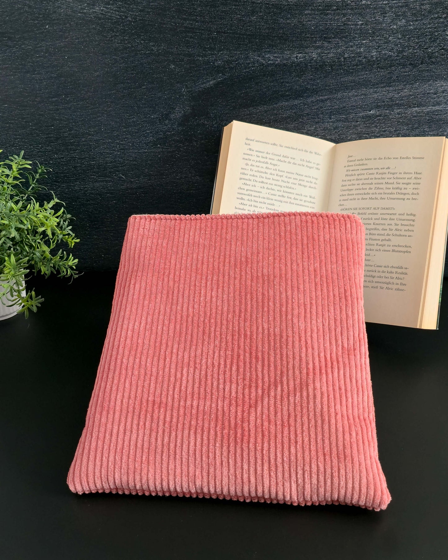 Buchhülle aus roséfarbenem Cord auf schwarzem Hintergrund