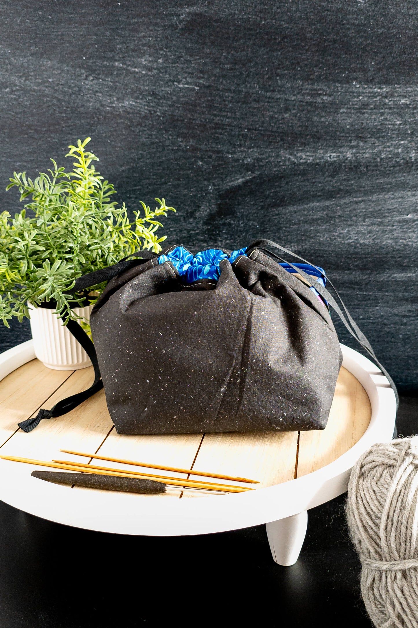 offene Handarbeitstasche mit Stricknadeln, Schere und blauer Wolle, perfekt für unterwegs