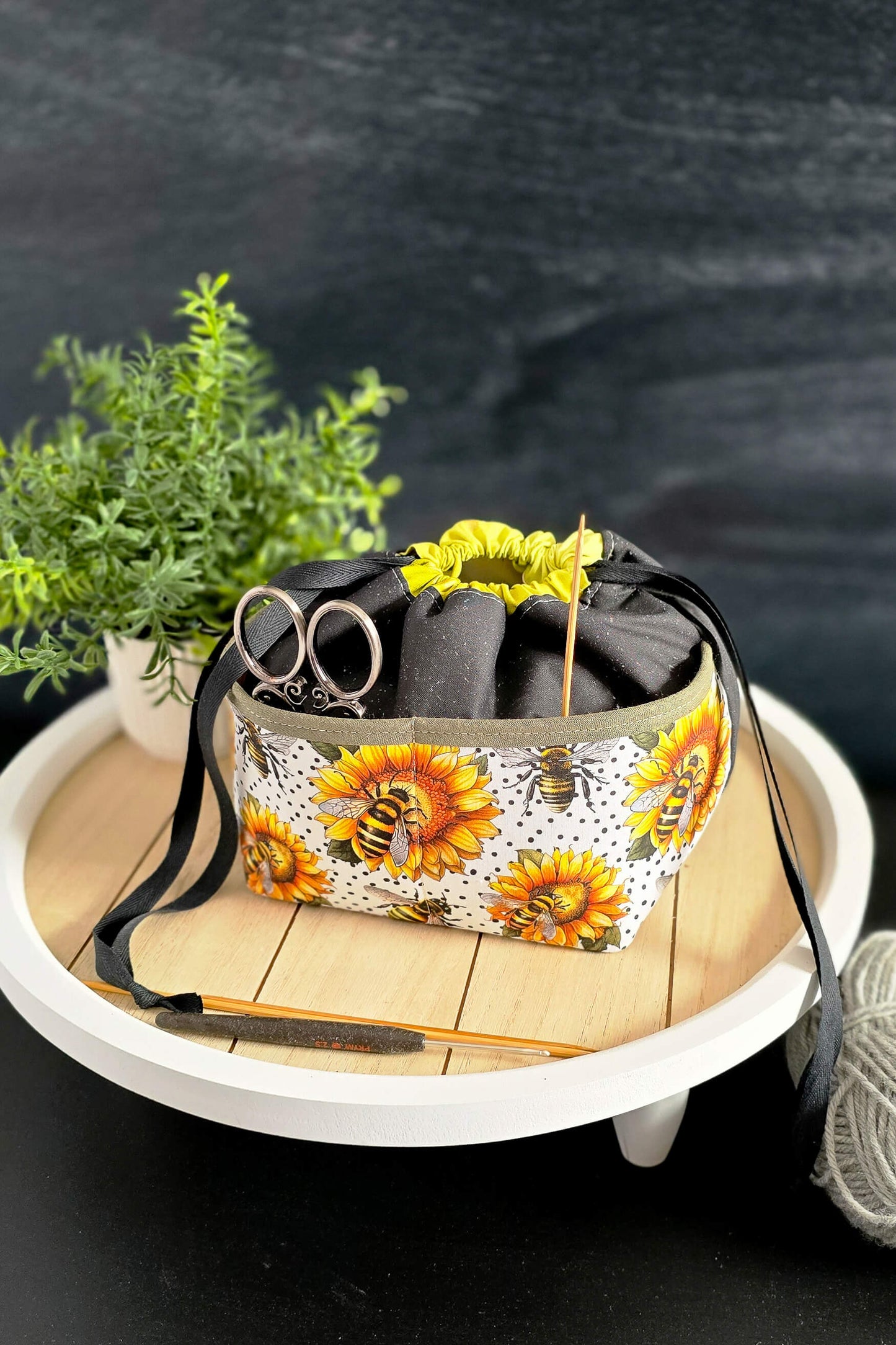 handgenähte Projekttasche „Sonnenzauber“ mit Sonnenblumen- und Bienenmuster, gefüllt mit Strickzubehör, auf einem dekorativen Tablett präsentiert