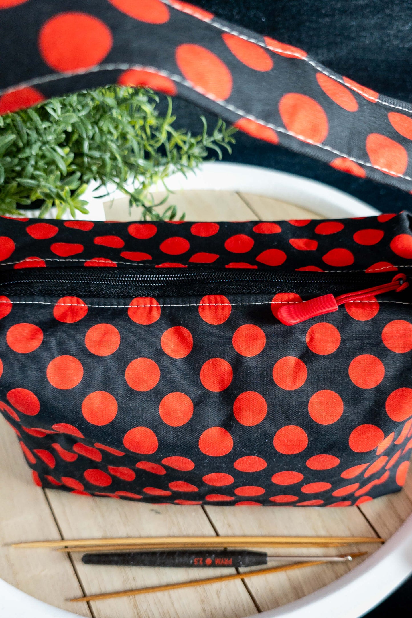 Friggs Bag „Lava Dots“ auf Holztisch mit Strickzubehör – praktischer und stylischer Projektbeutel in Action.