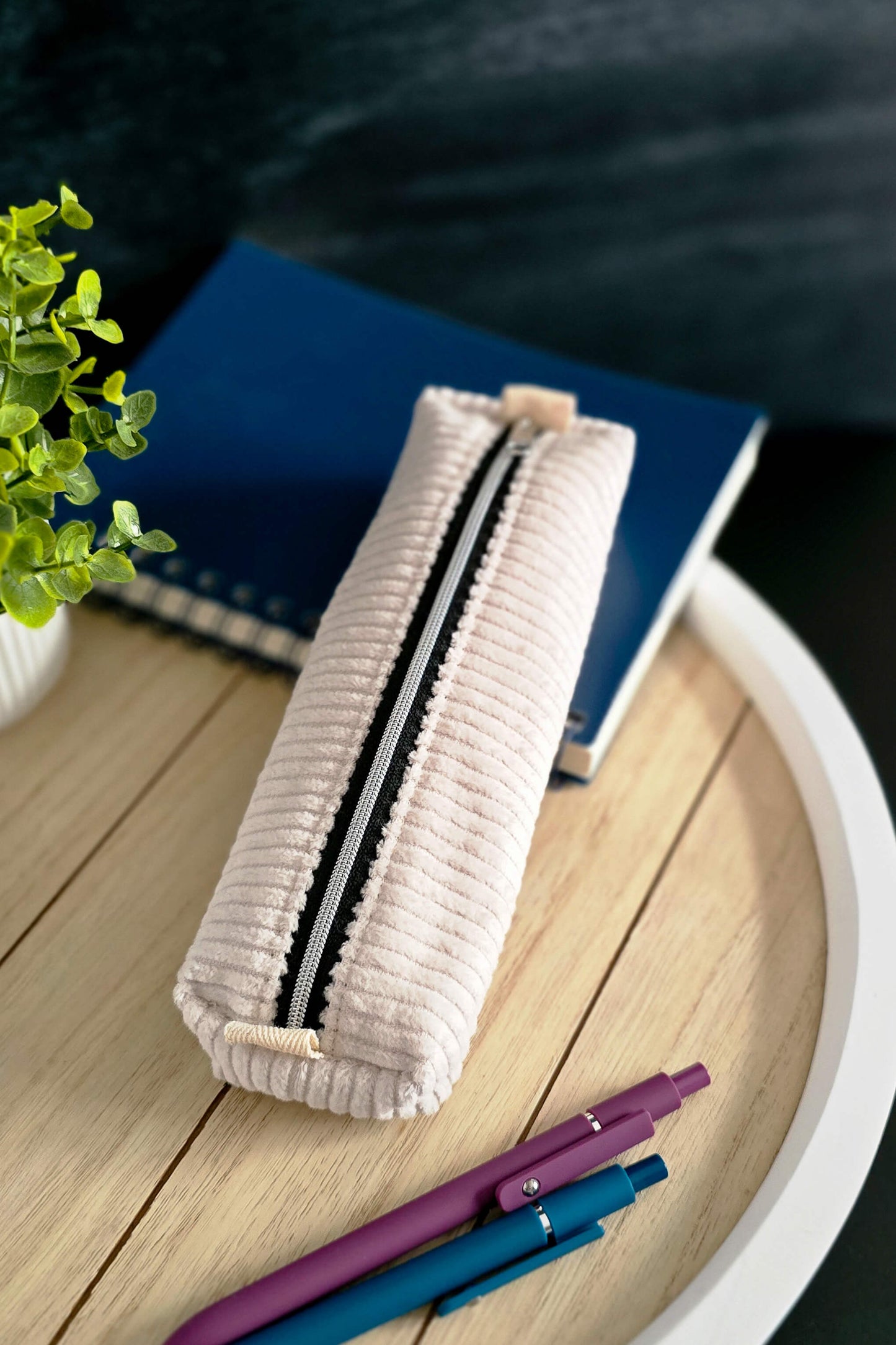 Stiftetasche aus cremefarbenem Cordstoff auf Tablett mit Stiften und Notizbuch