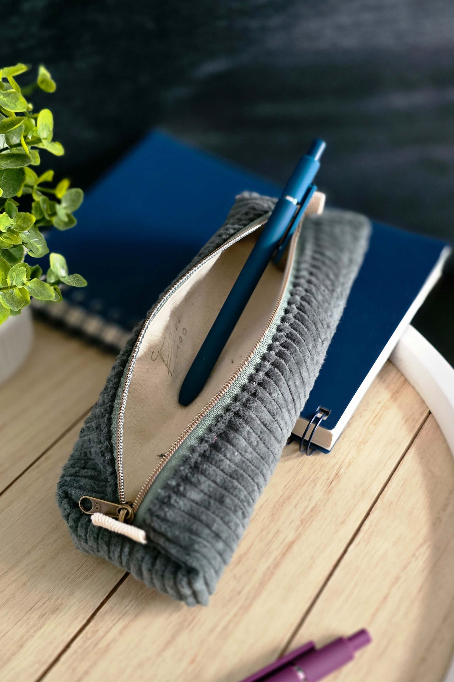 Stiftetasche neben Notizbuch und Stiften auf einem hellen Schreibtisch arrangiert