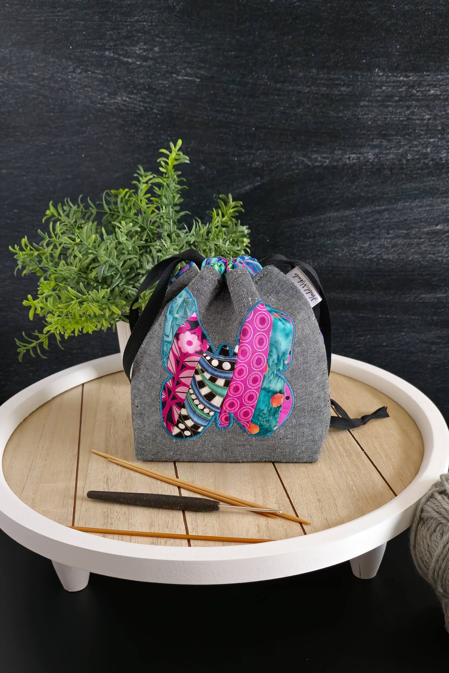 Detailansicht der handgenähten Projekttasche mit farbenfrohem Schmetterlingsmotiv auf grauem Stoff