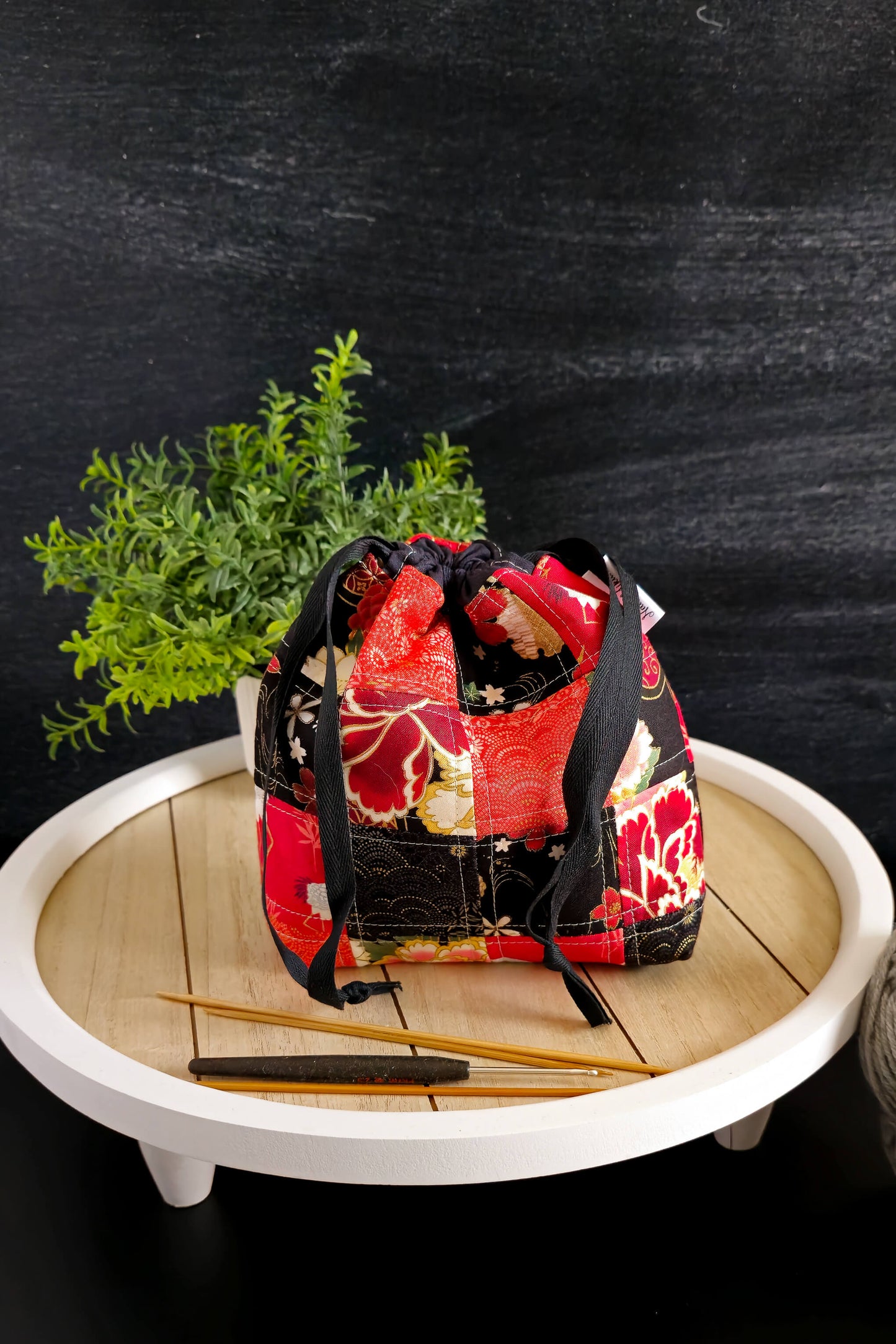 Kyoto Blossom Zubehörtasche im Licht, umgeben von Strickutensilien, ideal als Geschenk für Strickfans