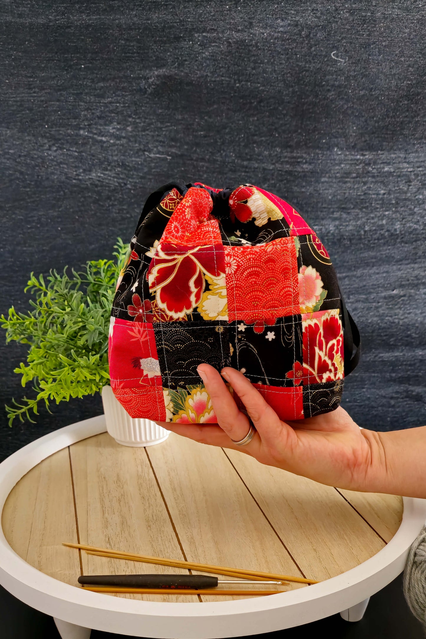 Die handgenähte Stricktasche neben Garnknäueln, perfekt für unterwegs und kleine Projekte