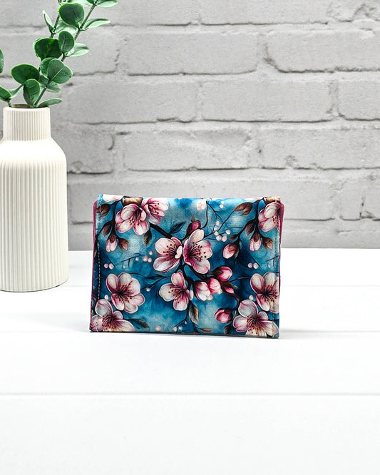 Kleine Mini Pouch mit rosa Kirschblütenmotiv auf blauem Grund und einem schwarzen Druckknopf. Handgenäht in Bayern von Nadelmikado.