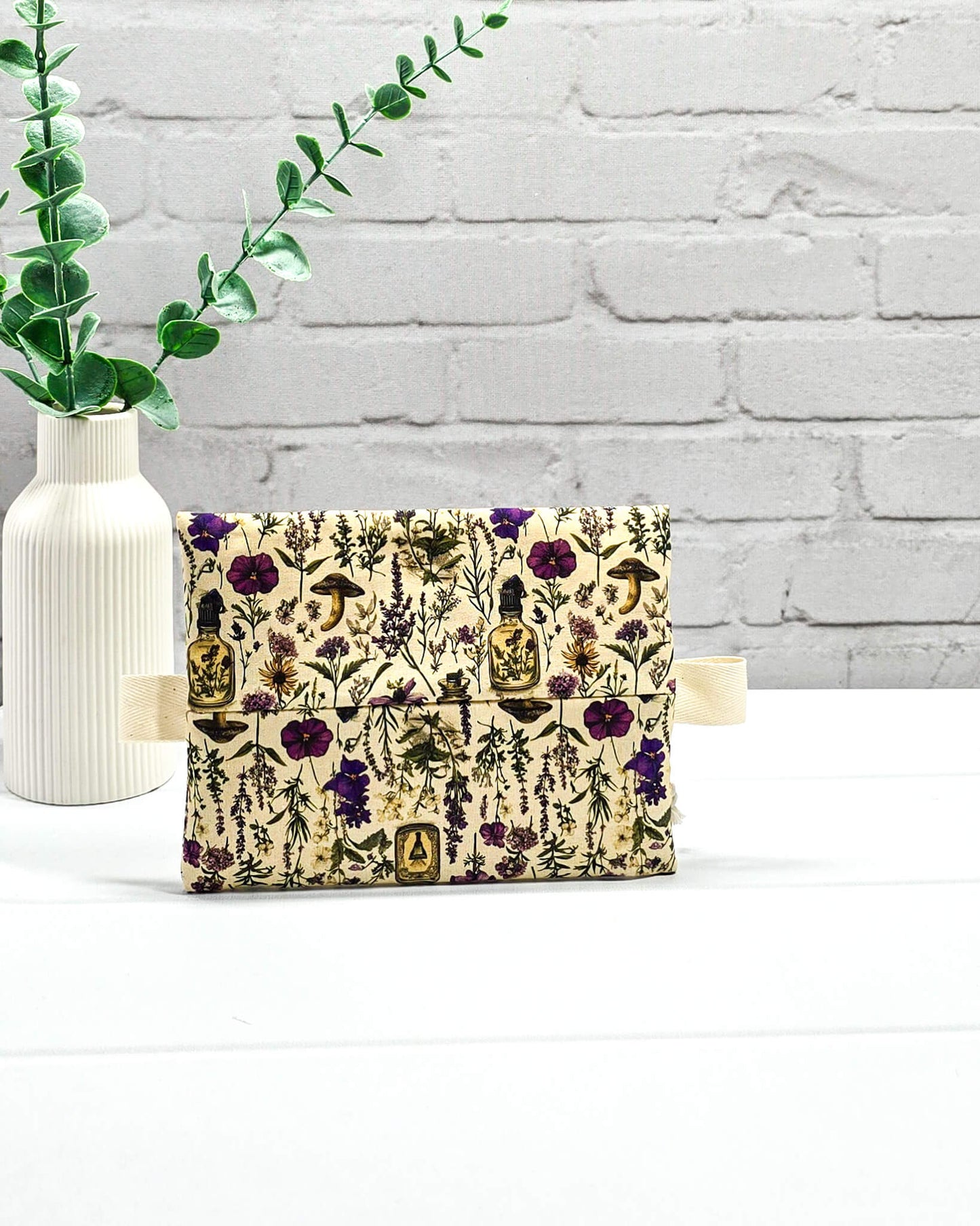 Kleine Reißverschlusstasche Mini Zip Pouch mit lila Reißverschluss, seitlichen hellen Laschen und botanischem Kräuterküche-Muster auf beigem Grund. Handgenäht in Bayern von Nadelmikado.