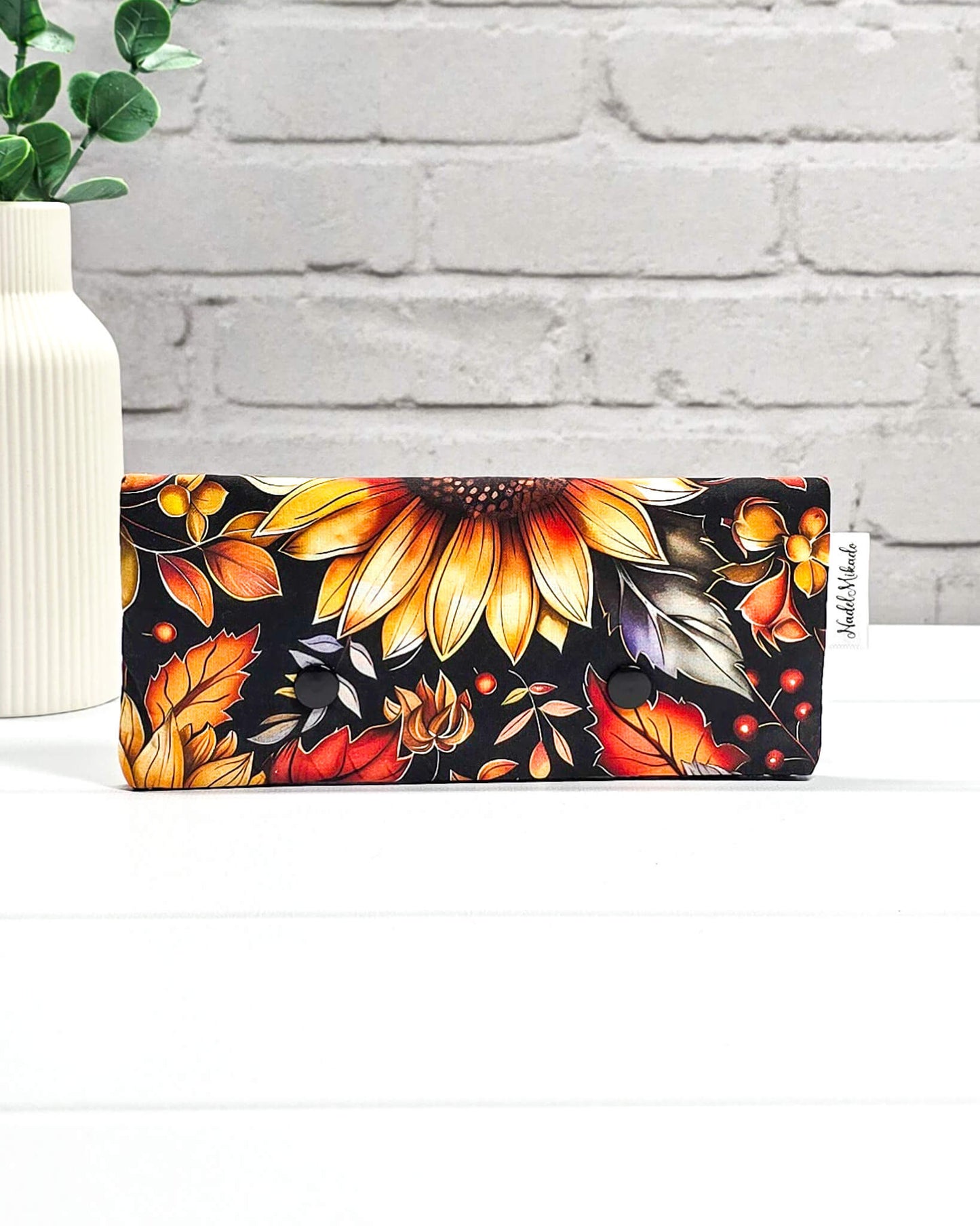 Nadelgarage für 15 cm lange Nadelspiele mit zwei schwarzen Druckknöpfen und großem Sonnenblumen-Motiv auf dunklem Grund. Handgenäht in Bayern von Nadelmikado.