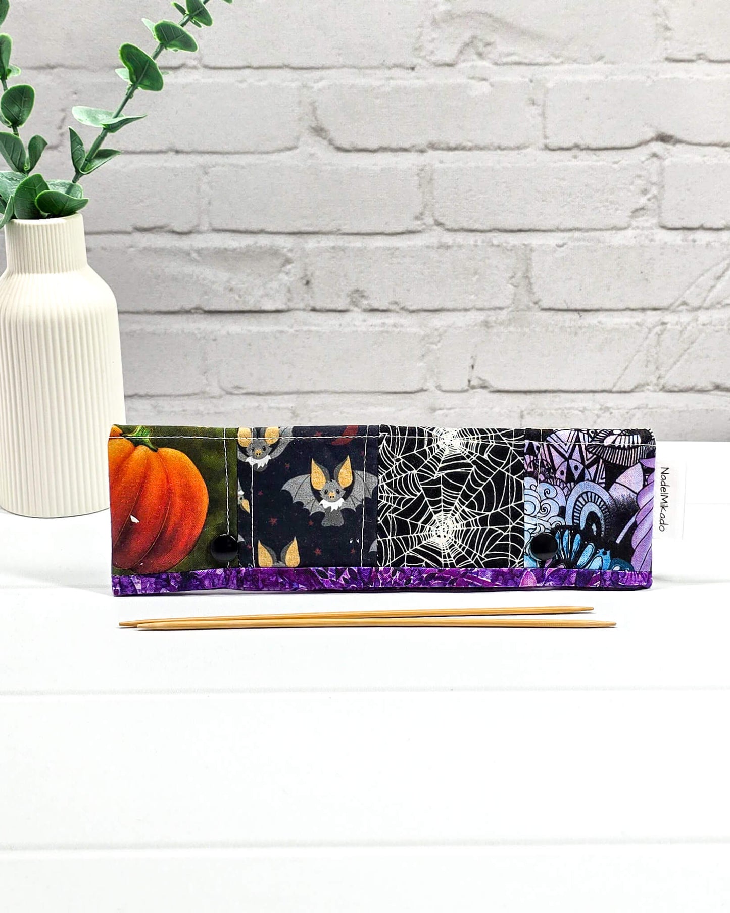 Nadelgarage für 20 cm Nadelspiele im Patchwork-Stil mit Halloween-Motiven wie schwarzen Katzen, Totenköpfen, Kürbissen und einem Vampirgnom-Design. Handgenäht in Bayern von Nadelmikado.