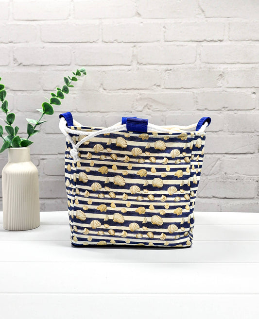 Projektbeutel Aska M aus blau-weiß quergestreiftem Stoff mit kleinen Muschelmotiven, zwei seitlich herausgeführten, hellen Kordeln und einer blauen Schlaufe an der Oberkante. Rice Bag. Handgenäht in Bayern von Nadelmikado.