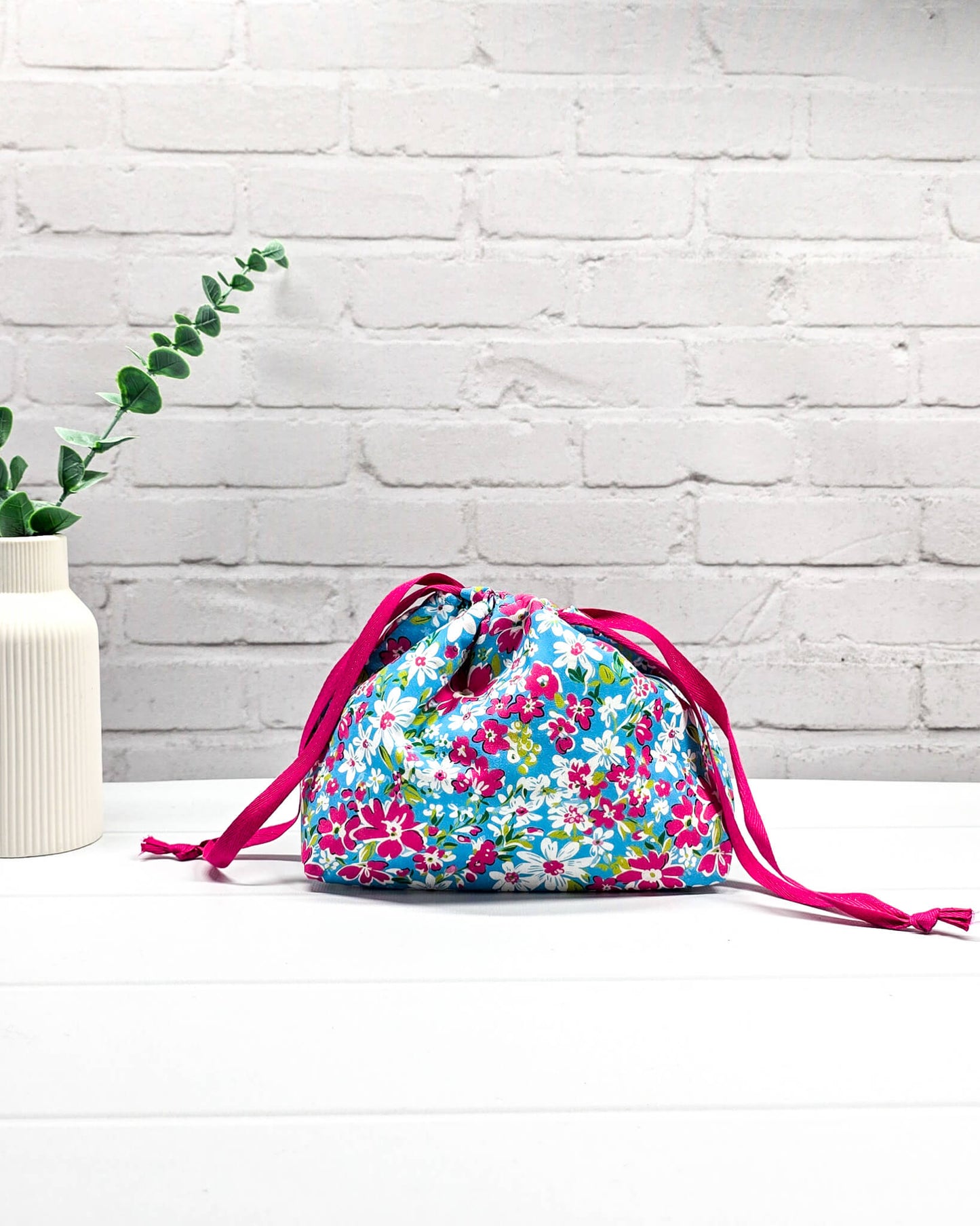 Projektbeutel Lyra mit pinken und weißen Blumen auf türkisfarbenem Grund und mit pinkem Kordelzug. Handgenäht in Bayern von Nadelmikado