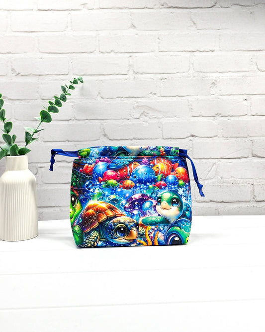 Projektbeutel Lyra mit einem bunten Motiv aus Meeresschildkröten und Fischen unter Wasser sowie blauem Kordelzug. Handgenäht in Bayern von Nadelmikado.