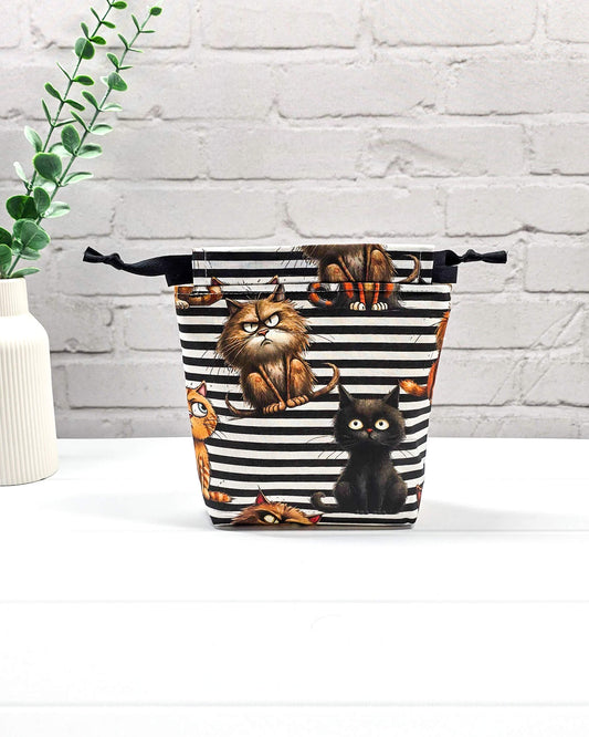 Kleiner Projektbeutel Tindra mit schwarz-weißem Streifenmuster, Grumpy-Cat-Motiven und schwarzem Kordelzug. Handgenäht in Bayern von Nadelmikado.