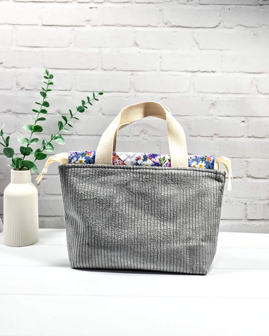 Grauer Projektbeutel Alva S aus Breitcord mit zwei kurzen, cremefarbenen Tragehenkeln oben und farbenfrohem Patchwork-Innenfutter, handgenäht in Bayern von Nadelmikado