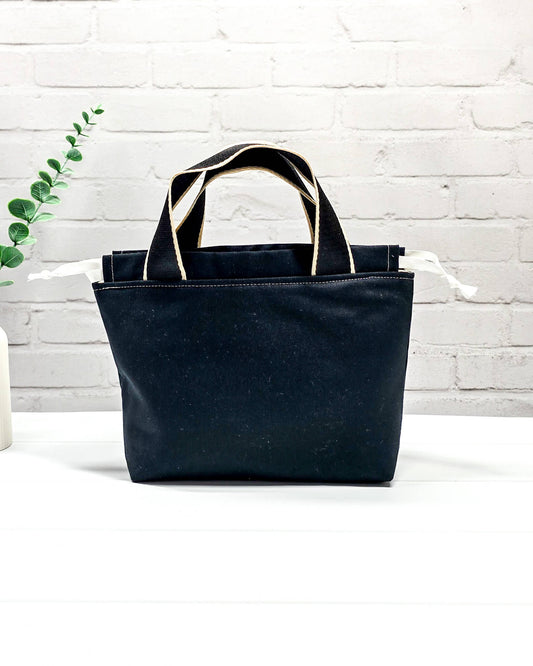 Projekttasche Alva S mit Schäfchenmotiv auf schwarzem Stoff, handgenäht in Bayern von Nadelmikado