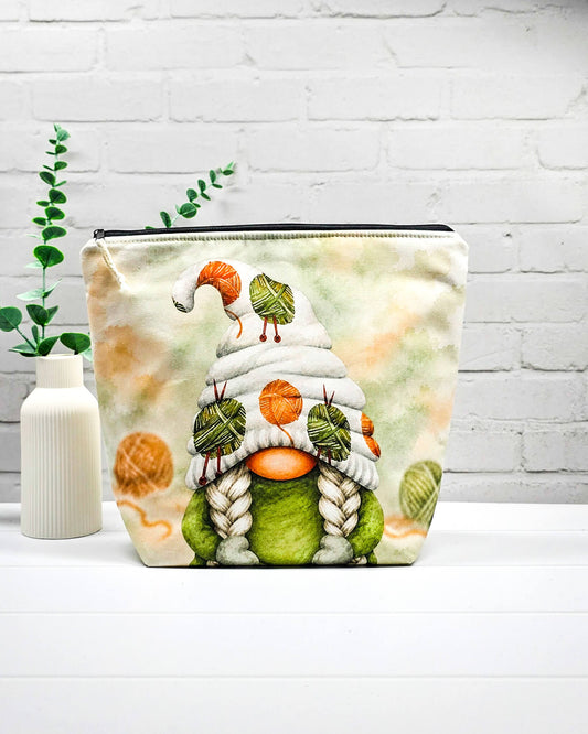 Strickprojekttasche Größe M mit Wichtel, heller Mütze, grünen und orangefarbenen Wollknäueln sowie schwarzem Reißverschluss. Handgenäht in Bayern von Nadelmikado.