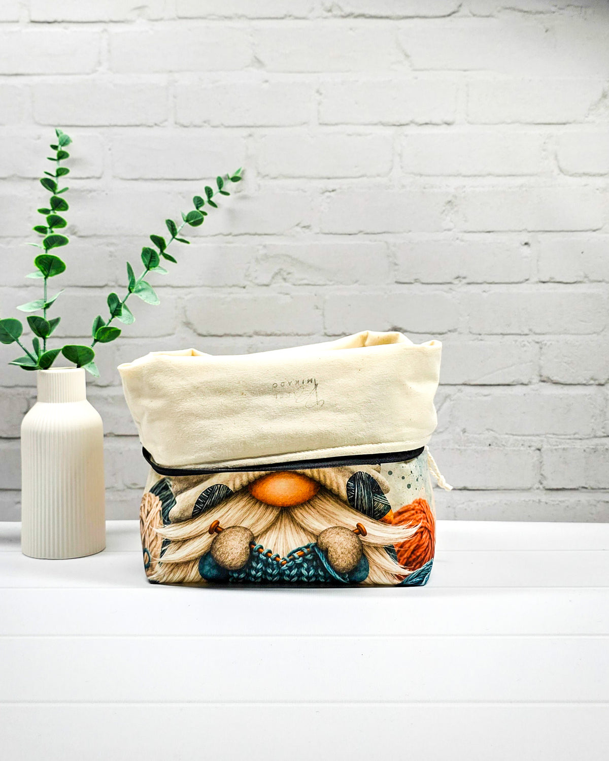 Strickprojekttasche Größe M mit Wichtel, heller Mütze und Wollknäueln in Petrol, Orange und Dunkelgrau sowie schwarzem Reißverschluss. Handgenäht in Bayern von Nadelmikado.