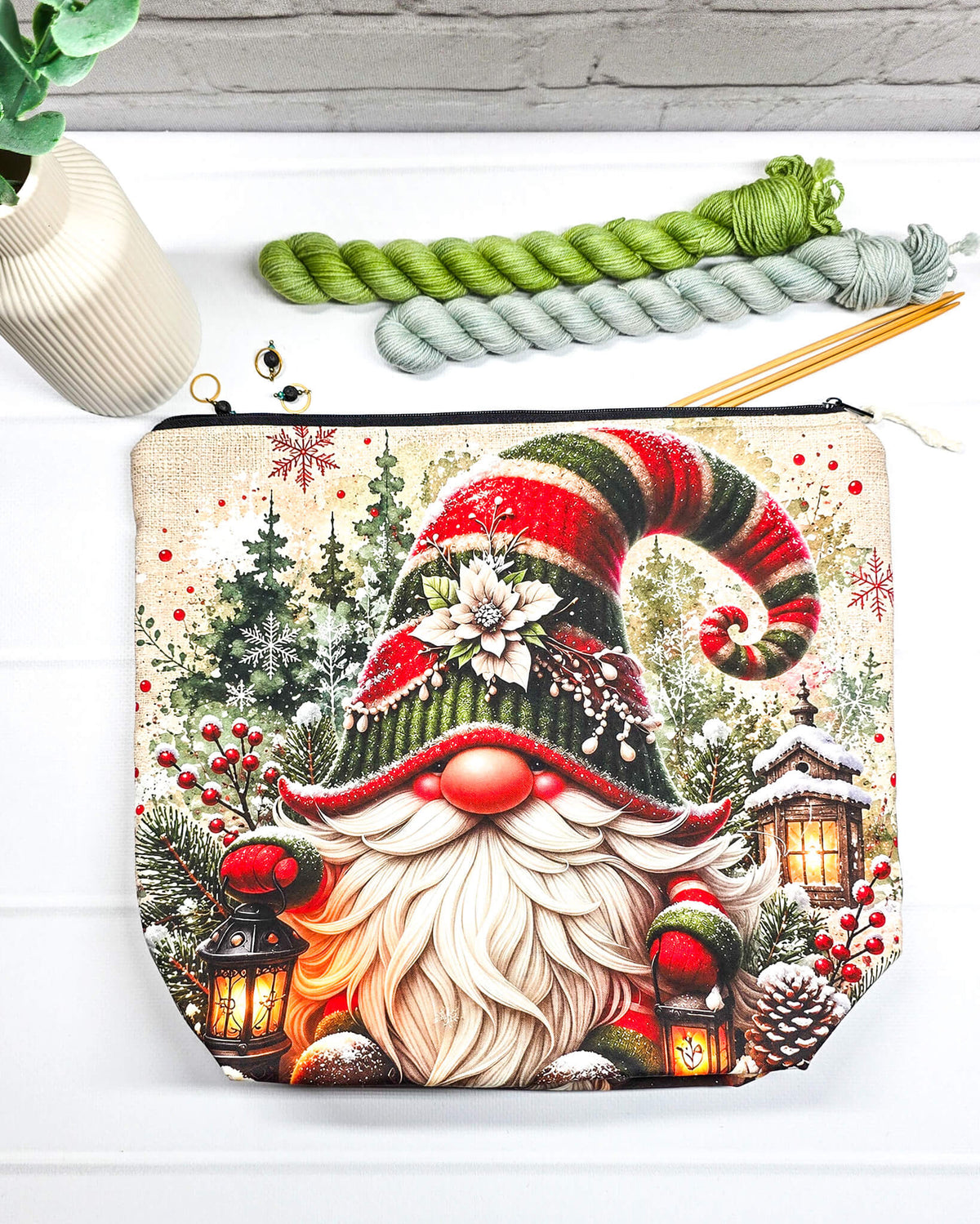 Projekttasche Isvind Größe M mit Weihnachtswichtel, rot-grüner Zipfelmütze, langem weißem Bart, verschneiten Tannen und leuchtenden Laternen. Mit Reißverschluss für Strickprojekte bis 400 g Wolle. Handgenäht in Bayern von Nadelmikado.
