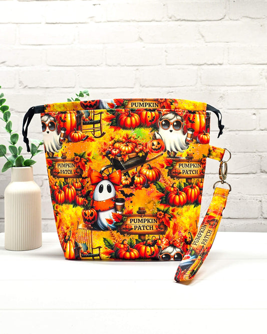 Projekttasche Tuva M aus buntem Baumwollstoff mit Geistern, Kürbissen, „Pumpkin Patch“-Schildern und schwarzem Kordelzug. Handgenäht in Bayern von Nadelmikado.
