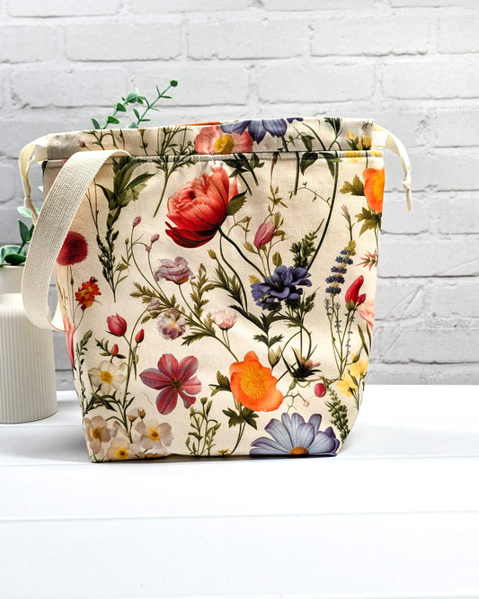 Projektbeutel mit buntem Blumenmuster für die sichere Aufbewahrung deines Tuch-Projekts unterwegs. Handgenäht in Bayern von Nadelmikado.