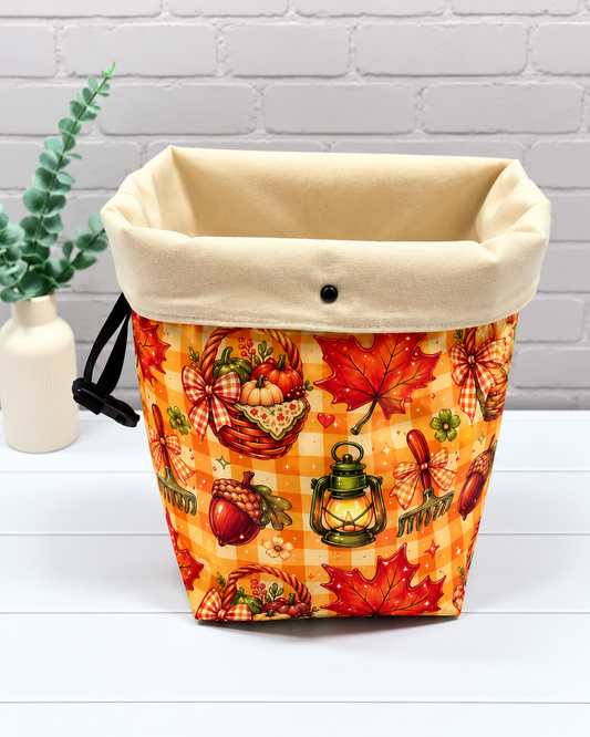 Rolltop-Projekttasche Rika mit orangefarbenem Karomuster, Herbstblättern, Eicheln, Laternen und Erntekörben mit Kürbissen. Handgenäht in Bayern von Nadelmikado.