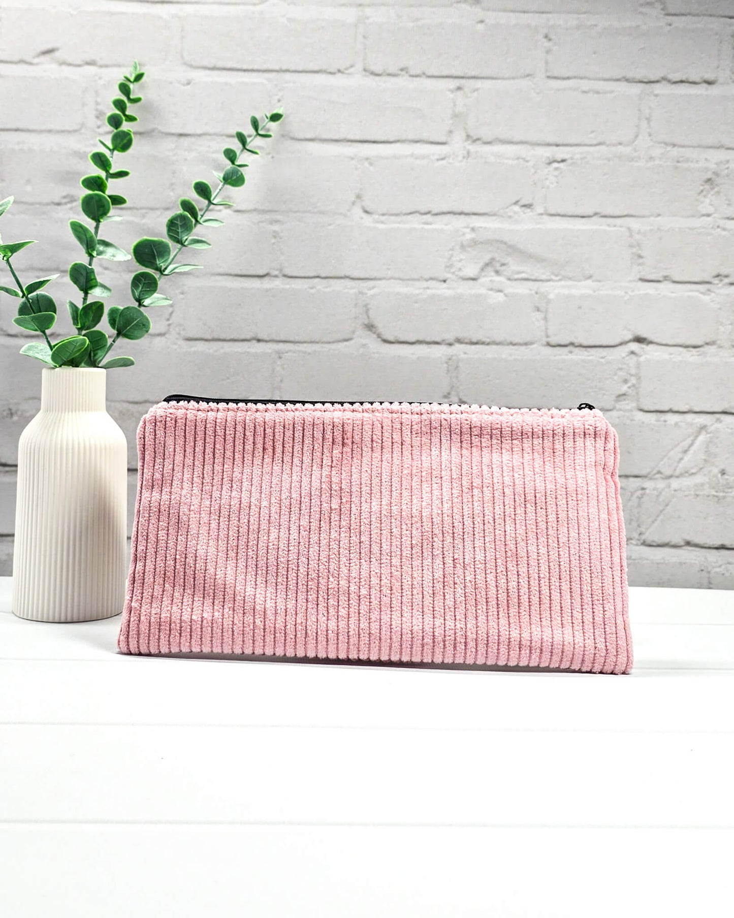 Kleine altrosafarbene Reißverschlusstasche aus Cord-Stoff für Strickzubehör, liegend auf weißem Untergrund mit einer Schere, Garnsträngen und Holznadeln. Handgenäht in Bayern von Nadelmikado.