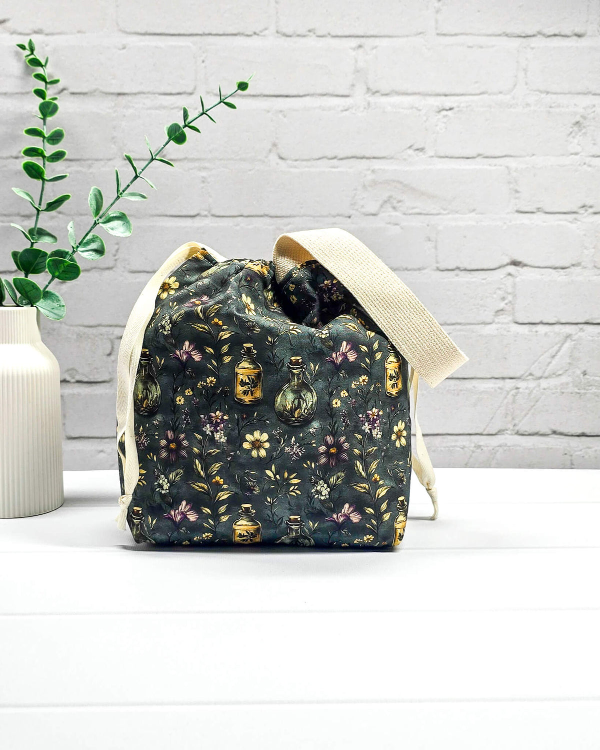 Stricktasche für bis zu 200 g Wolle im dunklen Botanical Apothecary Design mit Blüten und nostalgischen Apothekerfläschchen. Handgenäht in Bayern von NadelMikado.