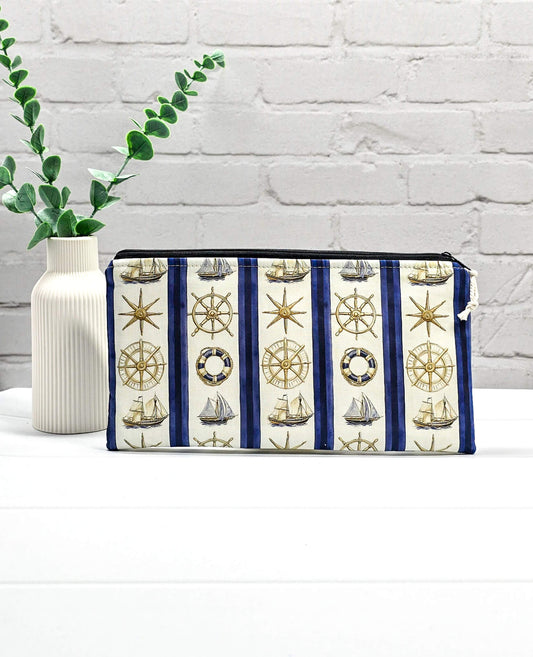 Flache, rechteckige Zip Pouch Runa mit maritimen Motiven wie Segelschiffen und Steuerrädern zwischen blau-weißen Streifen, handgenäht in Bayern von Nadelmikado.