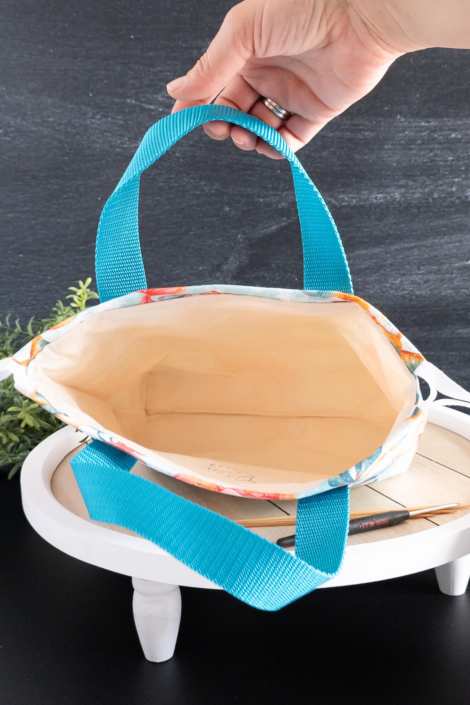 Nahaufnahme der Nähte und Trageriemen der handgemachten Stricktasche in Türkis
