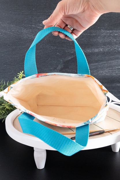 Nahaufnahme der Nähte und Trageriemen der handgemachten Stricktasche in Türkis
