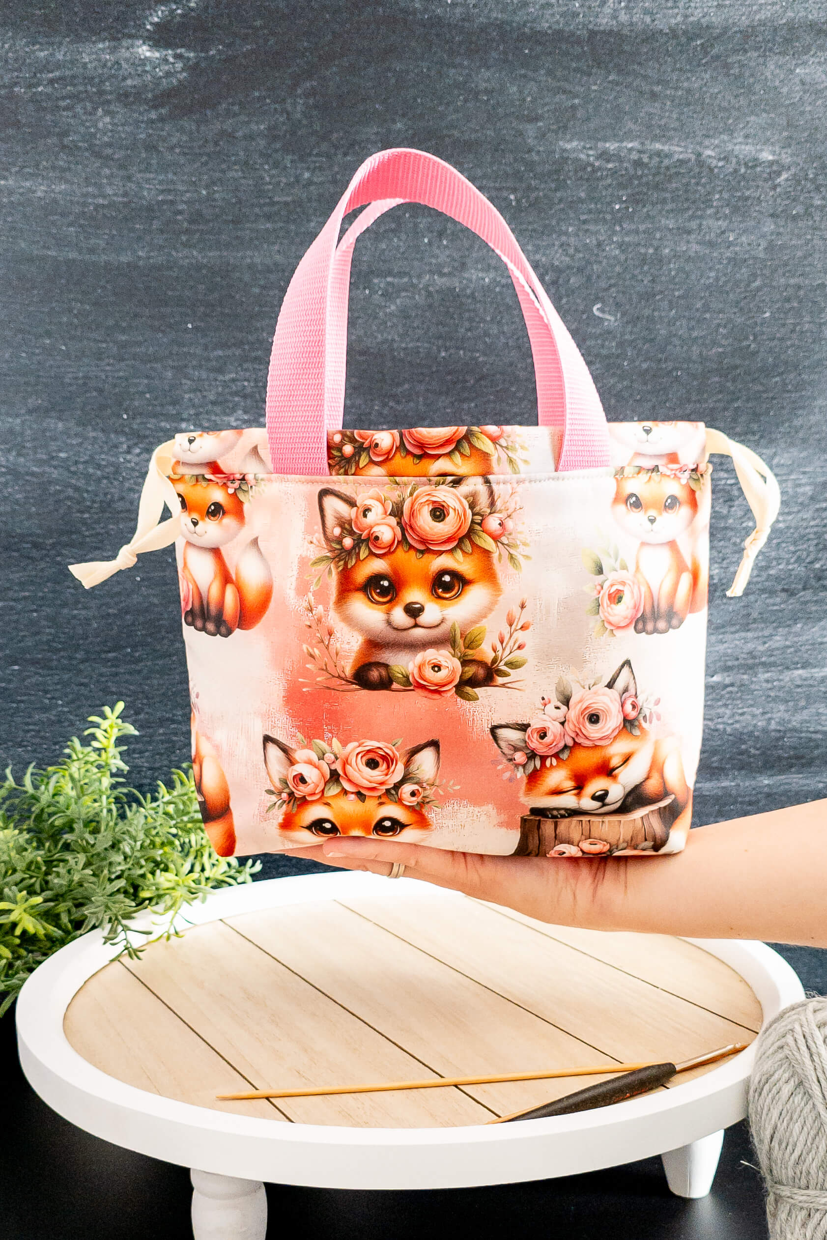 Die Alva Bag Foxy Bloom auf einem Tisch mit Strickzubehör – stilvoll und praktisch zugleich.