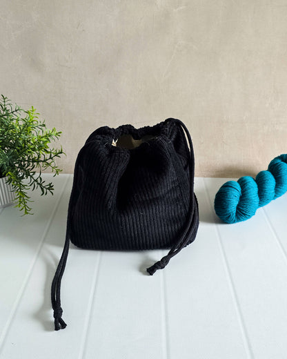 Schwarze Projekttasche aus Cord mit Kordelzug – für bis zu 400 g Wolle. Handgenäht & edel.