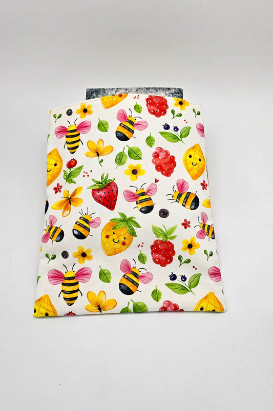 Detailansicht der gepolsterten Buchhülle mit buntem Design aus Bienen, Erdbeeren, Ananas und Blumen.