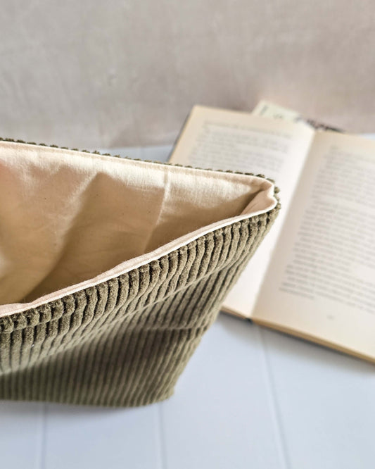 Olivgrüne Buchhülle aus Cordstoff, frontal vor aufgeschlagenem Buch fotografiert