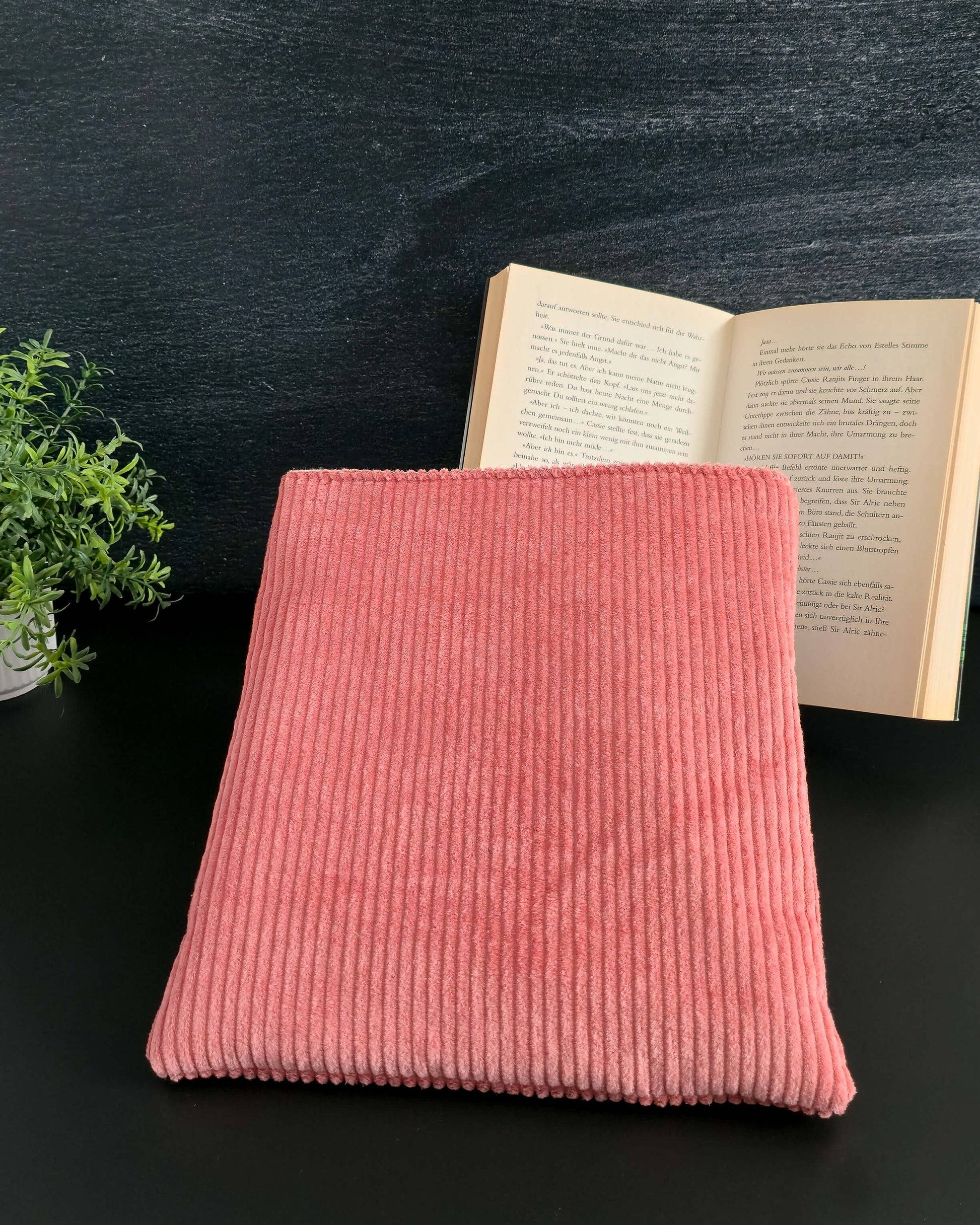 Buchhülle aus roséfarbenem Cord auf schwarzem Hintergrund