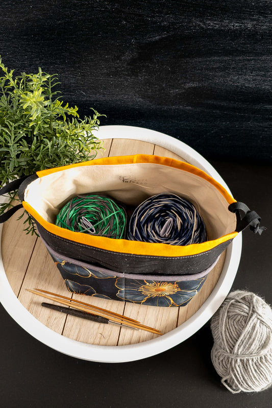Nahaufnahme der Stricktasche mit Kordelzug, Wolle und Stricknadeln ragen stilvoll heraus