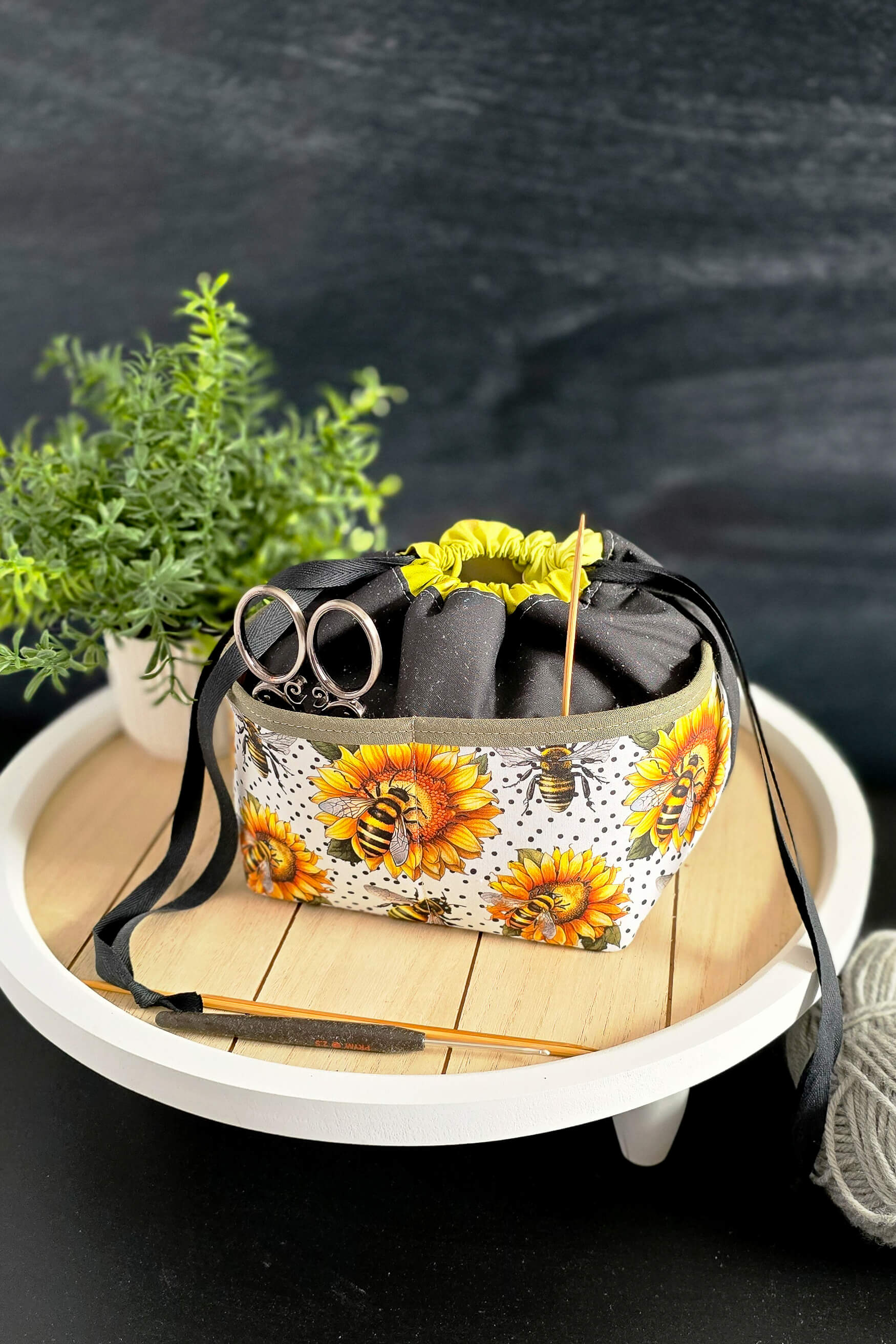 handgenähte Projekttasche „Sonnenzauber“ mit Sonnenblumen- und Bienenmuster, gefüllt mit Strickzubehör, auf einem dekorativen Tablett präsentiert