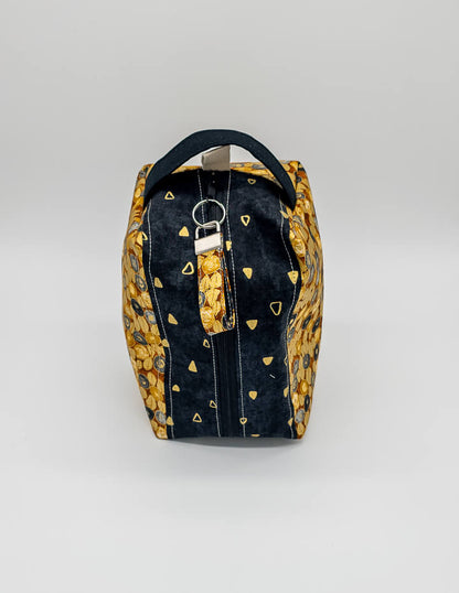 Fenja Bag Midnight Gold mit praktischem Griff und stilvollem Schwarz-Gold-Design.