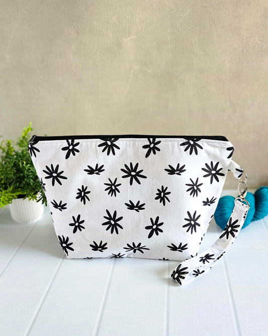 Handgenähte Projekttasche Isvind Daisy mit schwarzem Blumenprint auf weißem Grund