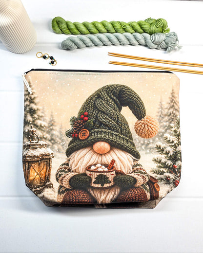 Projektbeutel mit Winterwichtel, gestrickter Mütze und Tasse vor verschneiter Kulisse, handgenäht in Bayern von NadelMikado.