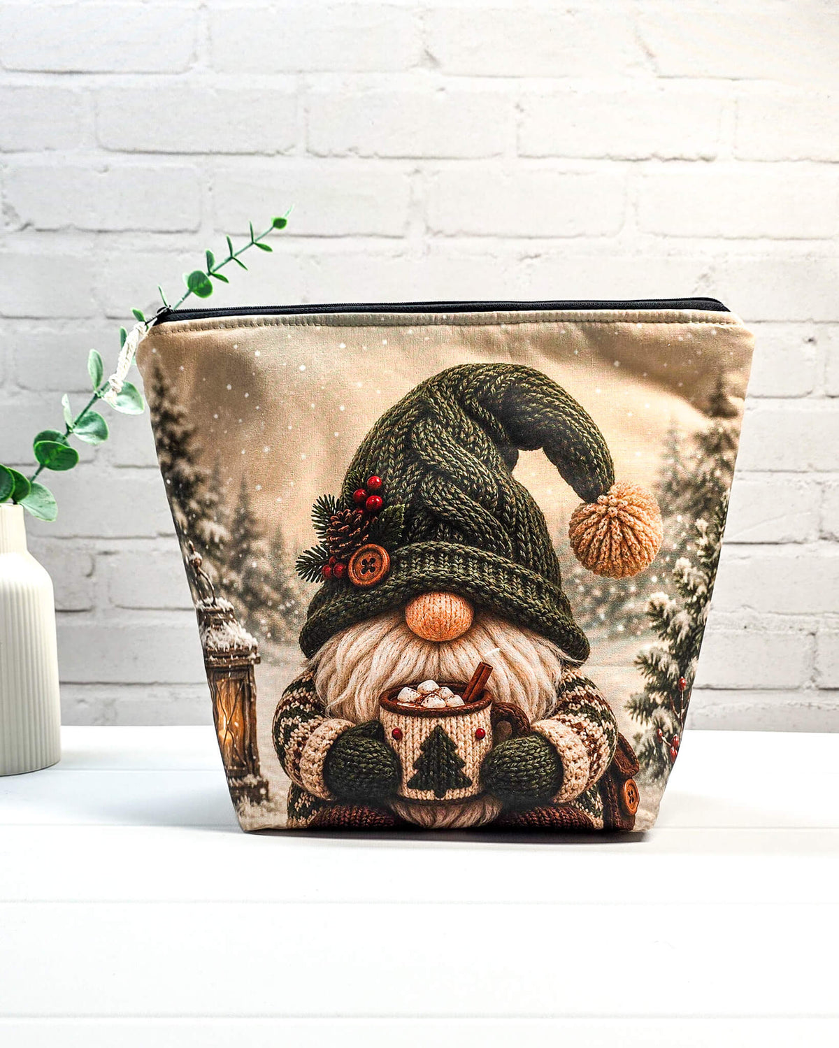 Projektbeutel mit Winterwichtel, gestrickter Mütze und Tasse vor verschneiter Kulisse, handgenäht in Bayern von NadelMikado.