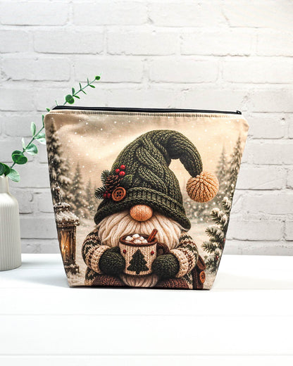 Projektbeutel mit Winterwichtel, gestrickter Mütze und Tasse vor verschneiter Kulisse, handgenäht in Bayern von NadelMikado.