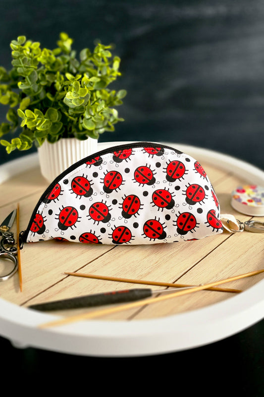 Zubehörtasche mit Marienkäfer-Print auf Holzteller mit Strickzubehör