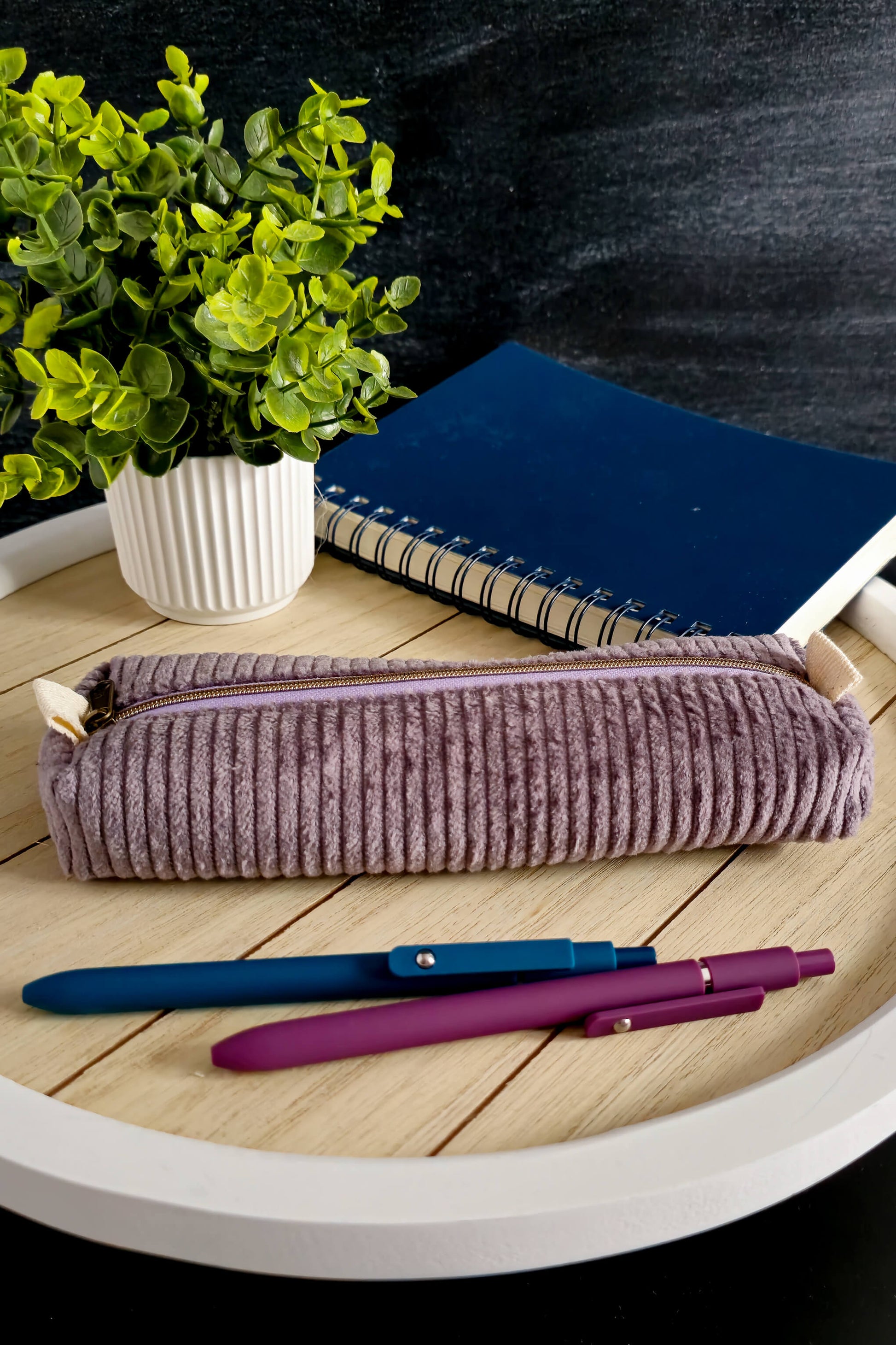 Handgenähte Stiftetasche aus lila Cordstoff mit Reißverschluss auf einem Holztablett