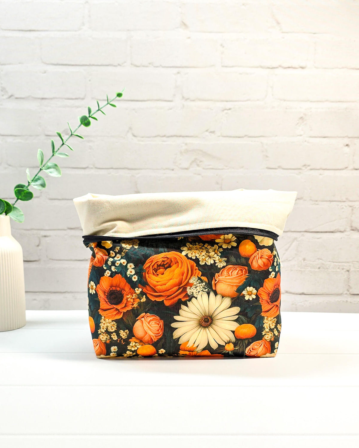 Projekttasche mit Reißverschluss und orangefarbenen sowie cremefarbenen Blüten auf dunklem Grund, handgenäht in Bayern von NadelMikado.