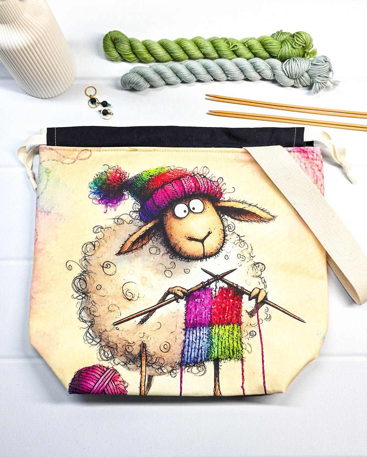 Stricktasche mit strickendem Schaf, bunter Mütze, Stricknadeln und Wollknäuel auf hellem Grund, handgenäht in Bayern von NadelMikado.